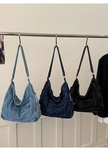 Detailed view of large denim tote bags in light blue, dark blue, and black with frayed edges