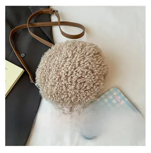 Detail of round beige shearling crossbody bag with a slim brown faux leather shoulder strap