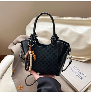 Détail du sac seau noir à damier avec poignée nouée et breloque en perles de bois colorées