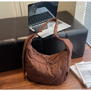 Détail d'un sac demi-lune matelassé marron foncé avec coutures ondulées et bandoulière