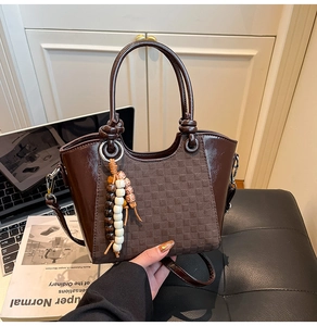 Détail du sac à main marron foncé montrant la texture damier et le gland en perles de bois