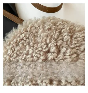 Close-up of soft beige faux shearling texture with brown leather strap detail