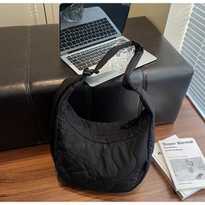 Détail du sac hobo matelassé noir avec coutures ondulées et bandoulière réglable