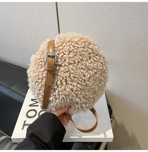 Detail of soft beige sherpa fleece texture and brown leather strap on round bag