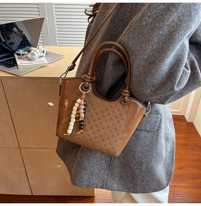 Détail du sac seau marron avec gaufrage en damier et perles de bois décoratives