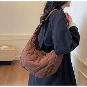 Close-up of brown quilted crossbody bag with stylish wavy pattern and soft texture