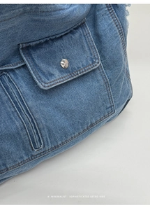Detailed macro view of denim tote bag with silver studs and orange contrast stitching
