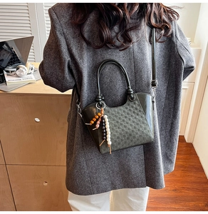 Détail de la texture tressée du sac seau vert avec pendentif ethnique en perles de bois