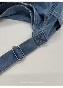 Detail of adjustable strap with silver buckle on blue denim tote bag, retro style