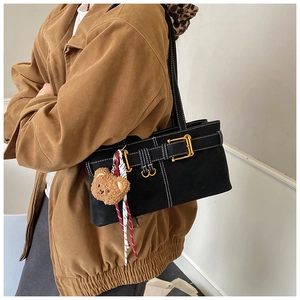 Detail of black underarm bag with gold buckle and cute brown bear plush charm