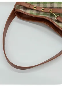 Dettaglio del tessuto a quadri vintage e tracolla in pelle marrone con fibbie dorate