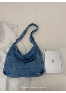Detail of blue denim hobo bag featuring external flap pocket and adjustable wide strap