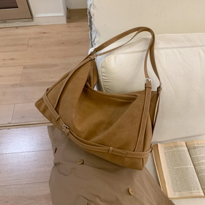 Macro detail of the caramel faux suede tote bag with silver buckle on a cozy sofa
