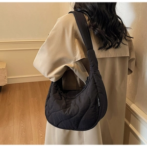 Détail du sac bandoulière matelassé noir en forme de croissant avec surpiqûres et étiquette