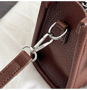 Detailaufnahme von braunem Leder mit Lychee-Maserung und polierter Silberschnalle