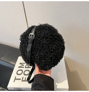 Detail of a black faux lamb fur round crossbody bag with adjustable leather strap