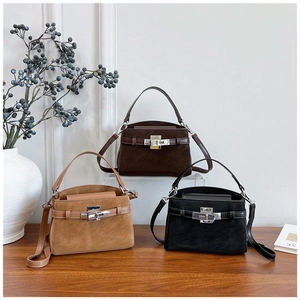 Close-up of three suede trapezoid handbags in brown and black with leather straps