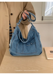 Close-up of retro large denim tote bag featuring frayed edges and metal button detail