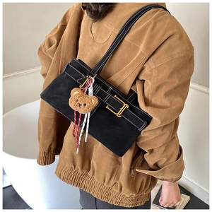 Detailed view of a black retro underarm bag with vintage metal buckles and a cute bear charm