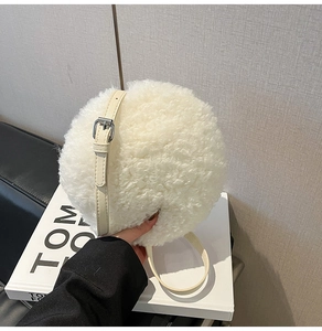 Close-up of off-white faux fur round crossbody bag with adjustable leather strap