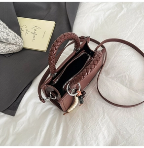 Detail einer braunen Leder-Mini-Tasche mit gewebtem Griff und Perlen-Anhänger-Dekor