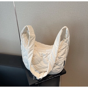 Détail du sac bandoulière blanc matelassé avec texture ondulée et étiquette de marque