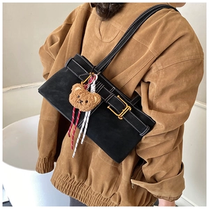 Detail view of black underarm bag with contrast stitching and plush bear charm