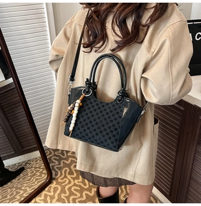 Détail d'un sac seau noir avec motif à damier et pendentif décoratif en perles de bois