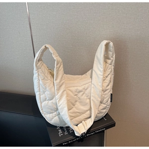 Détail du matelassage en cœur sur le sac bandoulière blanc cassé à large bandoulière
