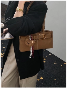 Close-up of caramel leather underarm bag with vintage buckle and bear charm detail