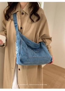 Detailed view of washed denim tote bag with vintage distressed holes and wide strap