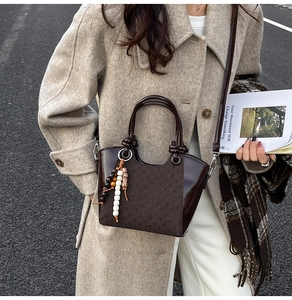 Détail du sac seau marron foncé avec motif à carreaux et pendentif décoratif en perles