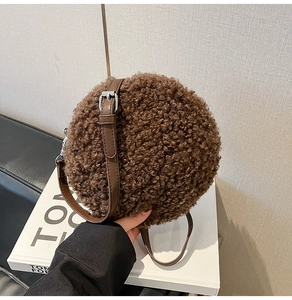 Detail of small round brown faux shearling crossbody bag with adjustable leather strap