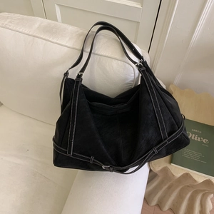 Detail of a black hobo bag with white stitching and adjustable silver buckles