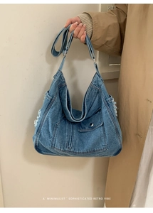 Detail of distressed edges and metal buckle pocket on large denim tote bag