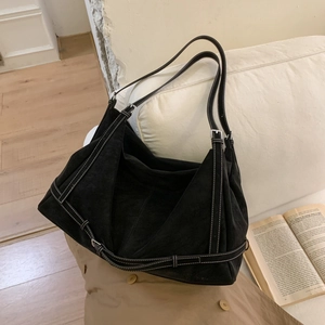 Detail of black suede tote bag featuring white contrast stitching and adjustable strap