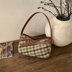 Dettaglio della borsa sottobraccio a quadri verdi e marroni su un tavolo vintage
