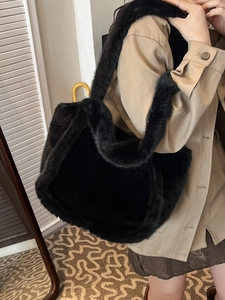 Large black faux fur tote bag with plush shoulder strap shown on a female model