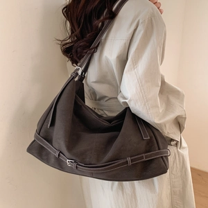 Detail of dark brown faux suede tote bag featuring white contrast stitching and buckle