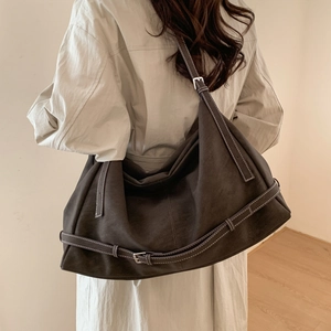 Close-up of vintage brown suede hobo bag with thick stitching and adjustable strap