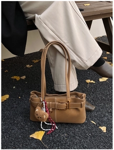 Detailed view of a brown faux leather underarm bag with decorative belt buckle and teddy charm