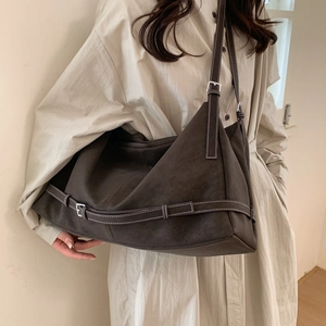 Detail of suede shoulder tote bag with white contrast stitching and metal buckle accents