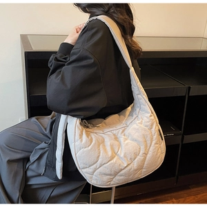 Gros plan sur le sac demi-lune matelassé gris clair avec surpiqûres ondulées