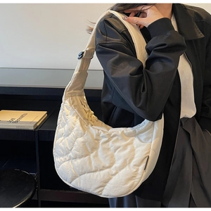 Détail d'un sac hobo blanc matelassé avec surpiqûres ondulées porté par un mannequin