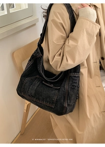 Detail of vintage washed black denim hobo bag with distressed edges and wide strap