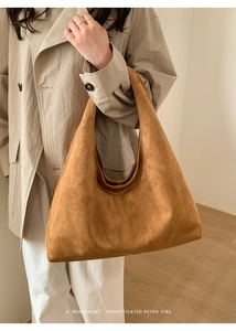 Détail du sac hobo en daim marron au design minimaliste porté sur un trench-coat beige