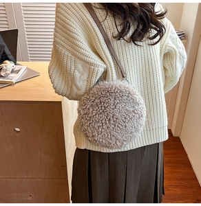 Detailed view of oatmeal fleece round crossbody bag with brown leather strap worn by model