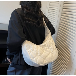 Détail de la vue arrière d'un sac à bandoulière matelassé blanc porté par un mannequin