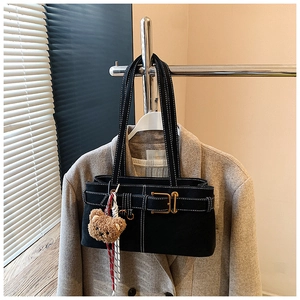 Detail of black canvas handbag with white contrast stitching and a plush bear charm