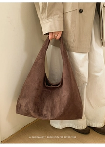 Détail du sac hobo en daim marron foncé porté avec une tenue d'automne minimaliste